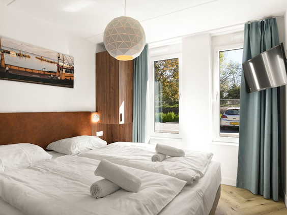 De moderne en sfeervolle slaapkamer in een vakantiehuis op Vakantiepark Volendam, met een opgemaakt tweepersoonsbed.
