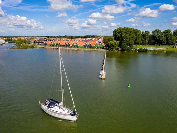 Luchtfoto van zeilboten op het Markermeer, met op de achtergrond de huisjes van Vakantiepark Volendam aan de waterkant.