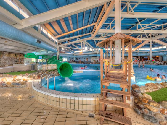 Het subtropisch zwemparadijs van Vakantiepark Weerterbergen met een houten speeltoestel en de waterglijbaan op de achtergrond.