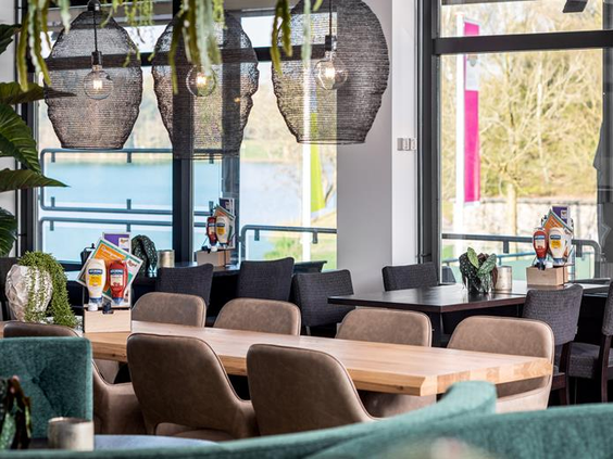 De modern ingerichte loungehoek in de plaza van Vakantiepark Weerterbergen, met comfortabele stoelen en grote ramen.