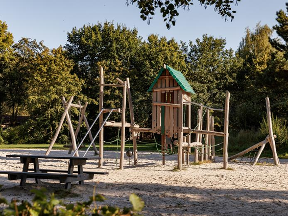 Een houten speeltoestel met boomhut en klimmogelijkheden in de buitenspeeltuin van Vakantiepark Weerterbergen.