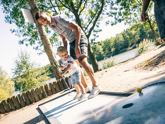 Een vader en zoon spelen samen een potje midgetgolf op de uitdagende buitenbaan van Vakantiepark Weerterbergen.