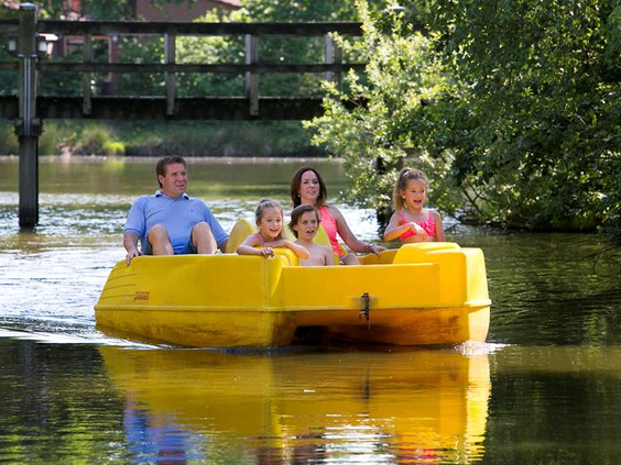 Een gezin met twee kinderen geniet van een zonnig tochtje op een gele waterfiets op het grote meer van Weerterbergen.