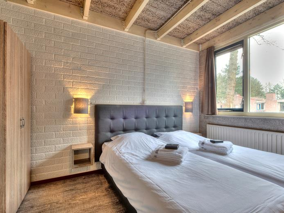Een sfeervolle, modern ingerichte slaapkamer met een comfortabel opgemaakt tweepersoonsbed in een bungalow op Weerterbergen.