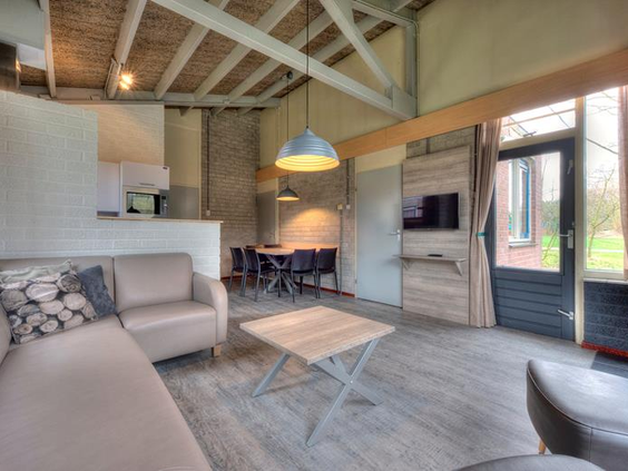De sfeervolle woonkamer van een vernieuwde en modern ingerichte bungalow op Vakantiepark Weerterbergen.