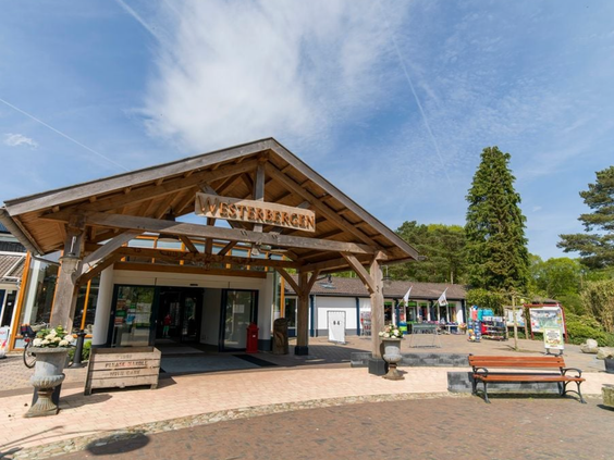 De houten entree van het centrumgebouw (Plaza) van Vakantiepark Westerbergen in Echten, Drenthe op een zonnige dag.