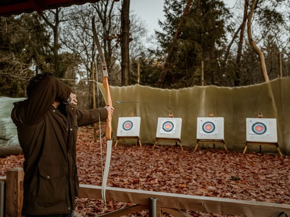 Een persoon richt met pijl en boog op de schietschijven bij de boogschietbaan in de bossen van Vakantiepark Westerbergen.