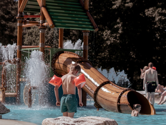 Kinderen met zwembandjes staan klaar om van de waterglijbaan in de waterspeeltuin van Vakantiepark Westerbergen af te glijden.