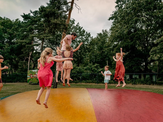 Kinderen en volwassenen springen hoog in de lucht op de grote air trampoline in de buitenspeeltuin van Vakantiepark Westerbergen.
