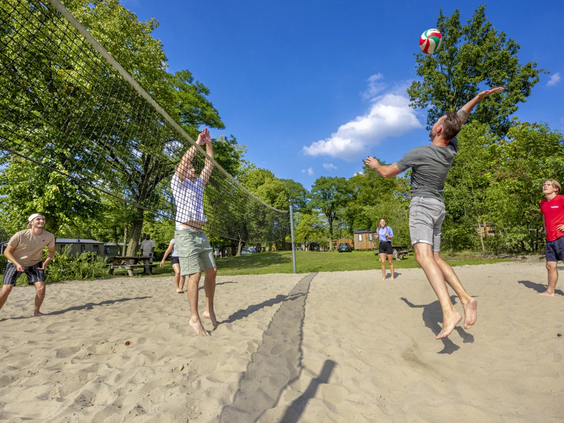 Jongeren spelen volleybal in het zand op het sportveld