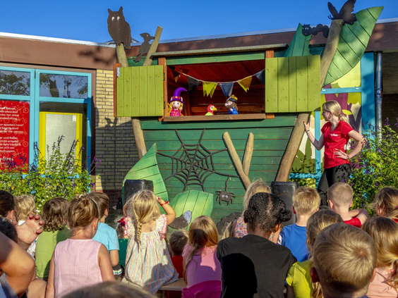 Kinderen kijken naar een poppentheater voorstelling op de camping