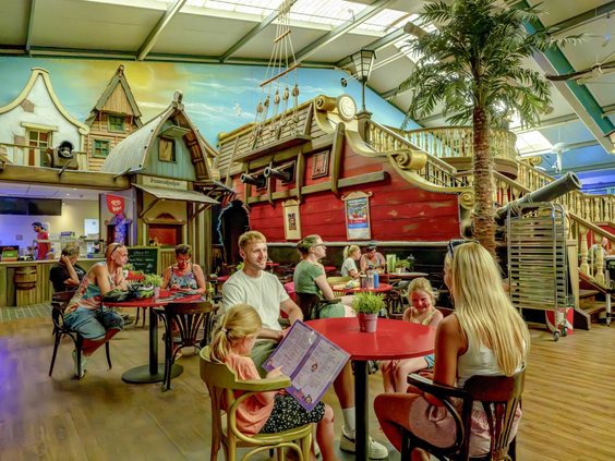 Gezinnen eten in het sfeervolle indoor restaurant van de camping