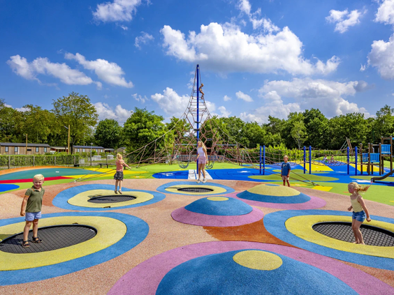 Overzicht van het buitenspeelveld met trampolines en speeltoestellen