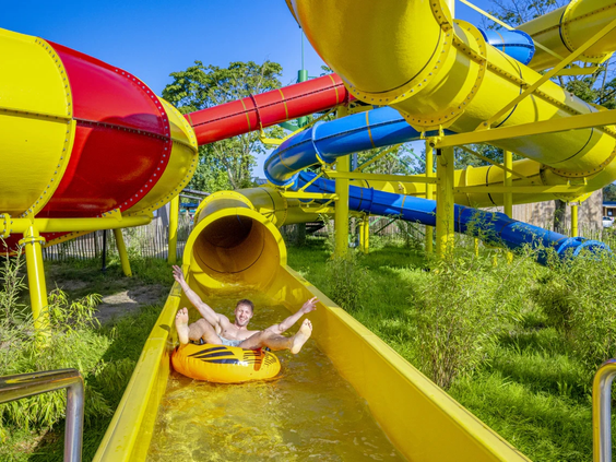 Kind glijdt met hoge snelheid van de gele waterglijbaan