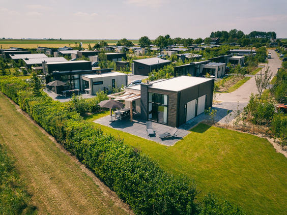 Luchtfoto van de moderne en luxe dijklodges met ruime tuinen op het nieuw aangelegde Vakantiepark Zeedijk.