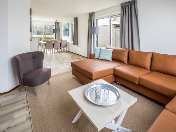 De sfeervolle woonkamer van een vakantiehuis op Zeeland Village, met een grote, comfortabele hoekbank.