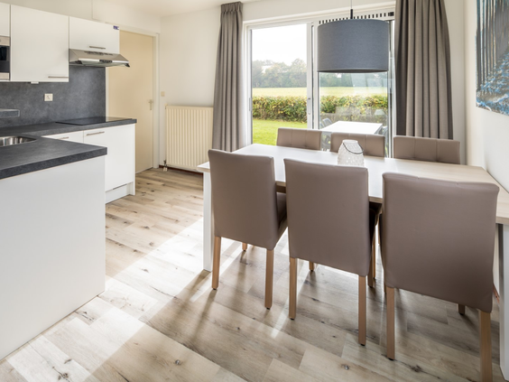 De open keuken met moderne eethoek in een vakantiehuis op Vakantiepark Zeeland Village, met uitzicht naar buiten.