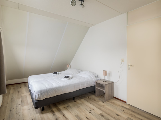 Een comfortabele slaapkamer met een tweepersoonsbed in een vakantiewoning op Vakantiepark Zeeland Village.