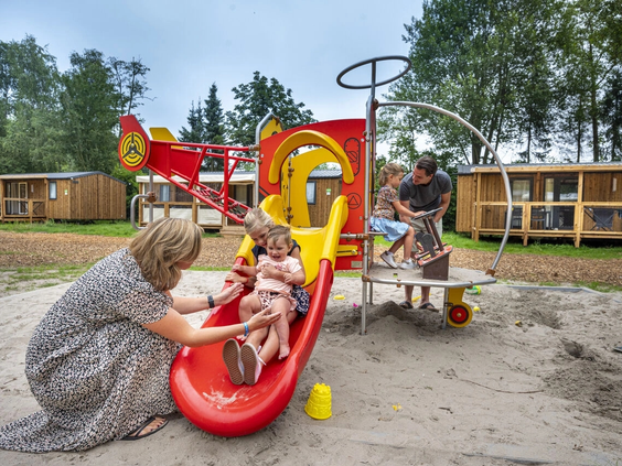 Een kleine rode glijbaan voor peuters in de speeltuin