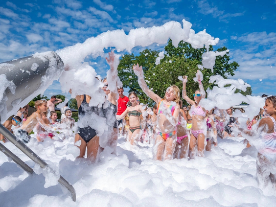 Kinderen vieren feest tijdens een schuimparty bij het zwembad
