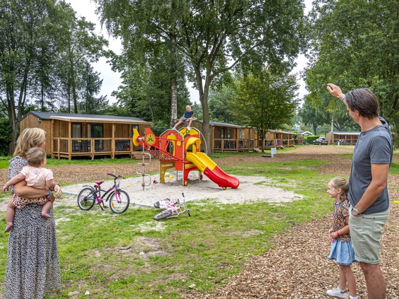 Kinderen spelend in een houten speeltuin in het zand op de camping