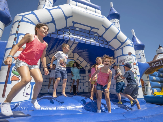 Kinderen springen op een groot opblaasbaar springkussen in de vorm van een kasteel