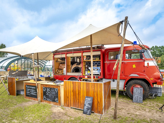 Een gezellige rode foodtruck voor snacks en drankjes op de camping
