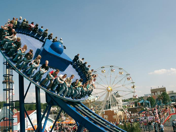 Een spectaculaire attractie in Movie Park Germany die hoog de lucht in zwiert, met het reuzenrad op de achtergrond.