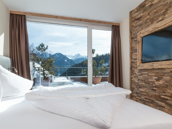 Luxe ingerichte slaapkamer met tweepersoonsbed dat uitkijkt over de bergen