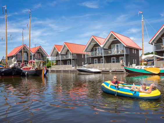 De karakteristieke waterwoningen van Waterpark Terherne in Friesland, gelegen aan het water met verschillende bootjes en Friese skûtsjes.