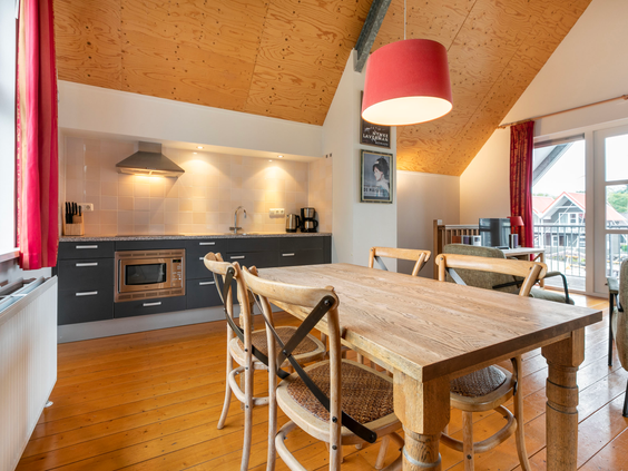 De ruime en lichte eethoek met een grote houten tafel in de open keuken van een waterwoning in Waterpark Terherne.