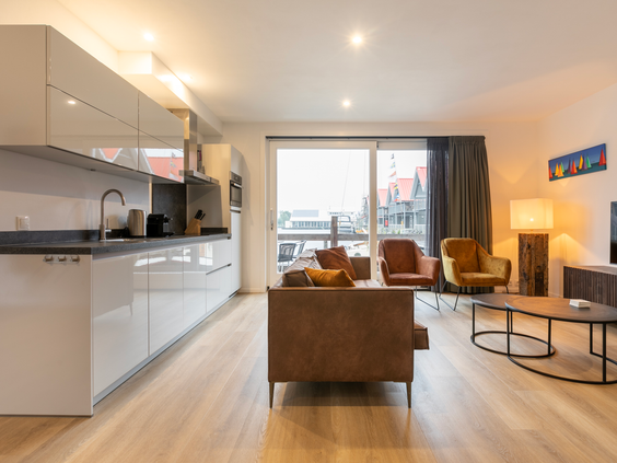 Het moderne en lichte interieur van de woonkamer en open keuken in een waterwoning bij Waterpark Terherne, met uitzicht op het water.