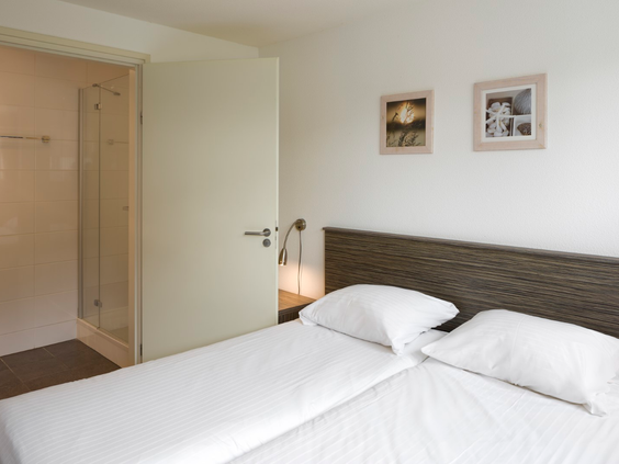Comfortabele slaapkamer met een opgemaakt tweepersoonsbed en een eigen en-suite badkamer op Waterpark Zwartkruis.