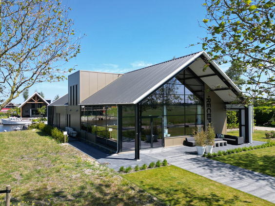 Het moderne, architectonische hoofdgebouw van Waterpark Zwartkruis met grote glazen pui, gelegen aan het water.
