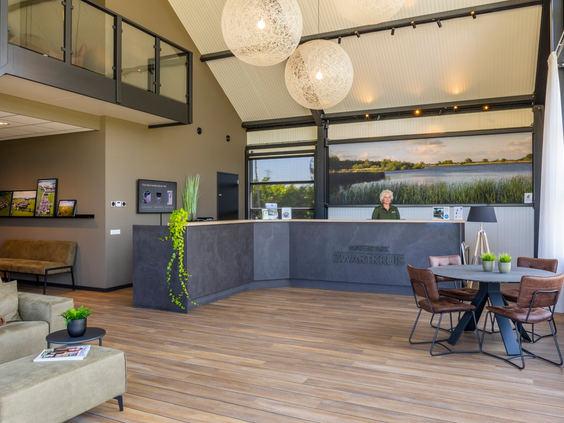 De ruime en lichte receptie en lounge van Waterpark Zwartkruis met een hoog plafond en modern interieur.