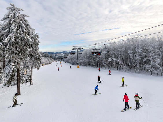 Skiërs en snowboarders op de brede, besneeuwde skipiste van het skigebied Winterberg, direct naast Center Parcs Park Hochsauerland.