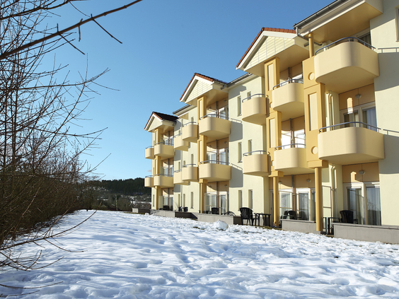 Het appartementencomplex van Center Parcs Park Hochsauerland op een zonnige winterdag, omringd door sneeuw.