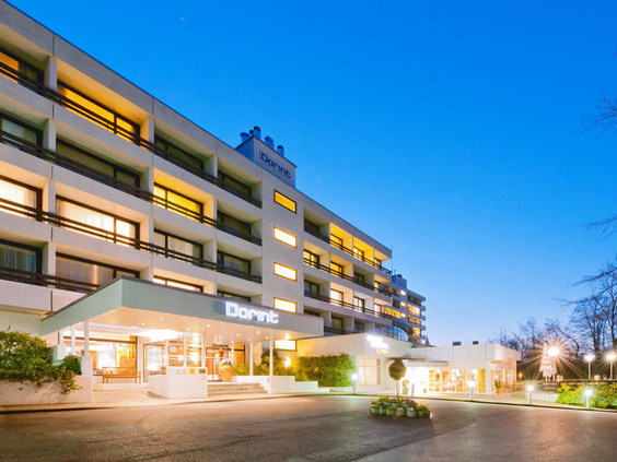 De moderne buitenkant van het verlichte Dorint Hotel & Sportresort Arnsberg-Sauerland in de avond.