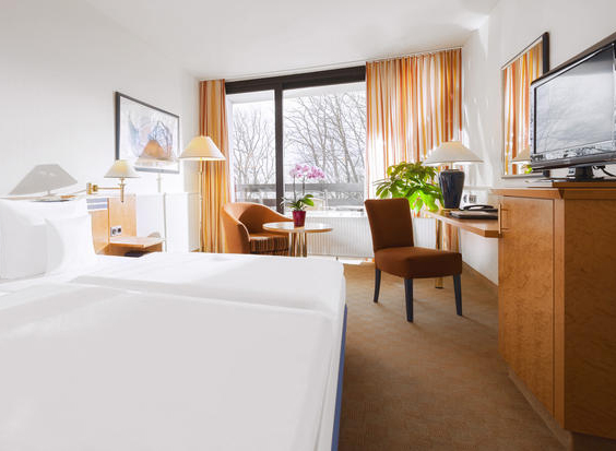 Een lichte en ruime familiekamer in Dorint Hotel Arnsberg, met een comfortabel bed en uitzicht op de winterse natuur.