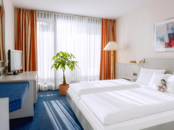 Een comfortabel opgemaakt bed in een van de hotelkamers van Dorint Hotel & Sportresort Arnsberg-Sauerland.