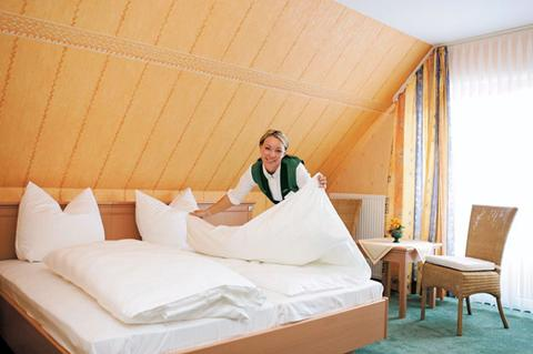 Een medewerker van Göbels Landhotel maakt een heerlijk fris bed op in een van de comfortabele hotelkamers.