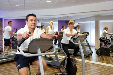 Gasten sporten op de loopband en andere fitnessapparaten in de moderne fitnessruimte van het hotel.