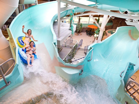 Twee kinderen gieren het uit van plezier terwijl ze samen in een band van de wildwaterbaan naar beneden suizen in het zwemparadijs.