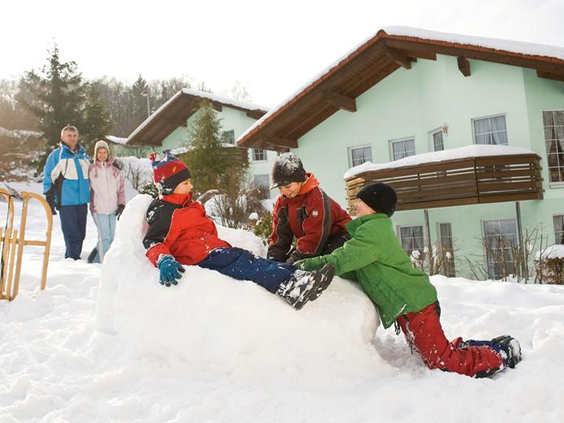 Kinderen maken een grote sneeuwpop voor hun vakantiehuis op vakantiepark Landal Salztal Paradies.