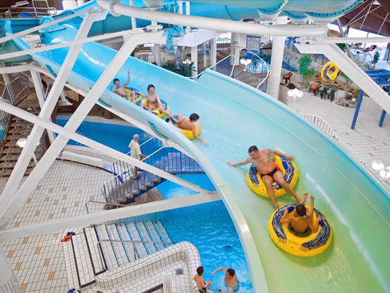 Kinderen en volwassenen glijden in grote gele banden van de lange, kronkelende waterglijbaan in het zwemparadijs.