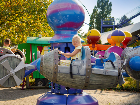 Een jong meisje geniet van een ritje in een draaimolen met op en neer bewegende vliegtuigjes in Wunderland Kalkar.