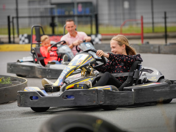 Een meisje en haar familie racen in snelle karts op de buitenkartbaan van attractiepark Wunderland Kalkar.