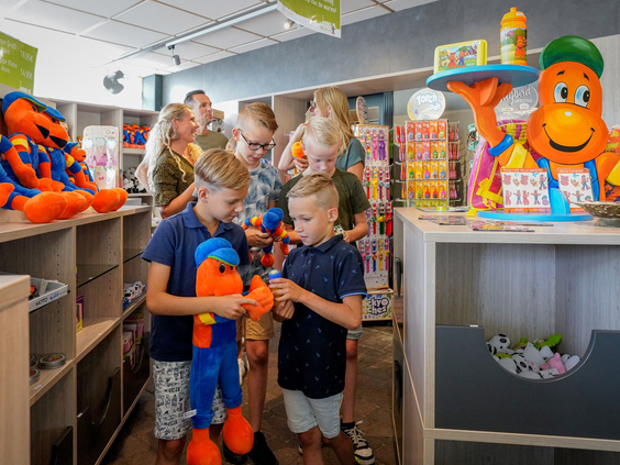 Kinderen kiezen een souvenir uit in de winkel van Wunderland Kalkar, vol met speelgoed en knuffels van de mascotte Kernie.