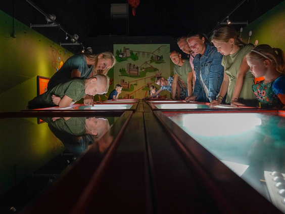 Een gezin kijkt naar de tentoonstelling in de verlichte vitrines binnenin de koeltoren van Wunderland Kalkar.