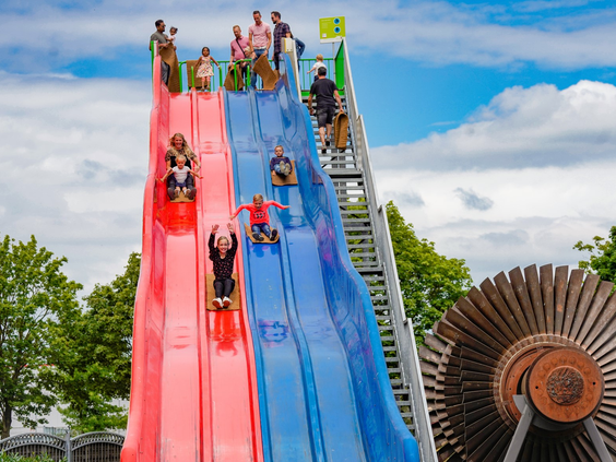 Kinderen glijden op matjes van een hoge, kleurrijke familieglijbaan in attractiepark Wunderland Kalkar.